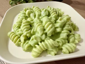 A delicious bowl of Avocado Broccoli Pasta garnished with fresh herbs and parmesan.
