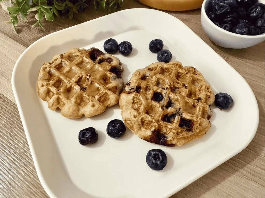Fluffy Blueberry Banana Waffles topped with fresh blueberries and banana slices.