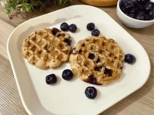 Fluffy Blueberry Banana Waffles topped with fresh blueberries and banana slices.