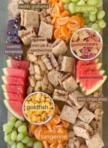 Colorful kids snacktime charcuterie board with fruits, cheeses, and healthy snacks.