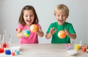 Kids making colorful DIY bouncy balls at home with a chemistry experiment kit.