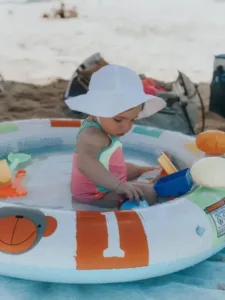 Family enjoying a sunny day at the beach with a baby, showcasing beach fun and safety.