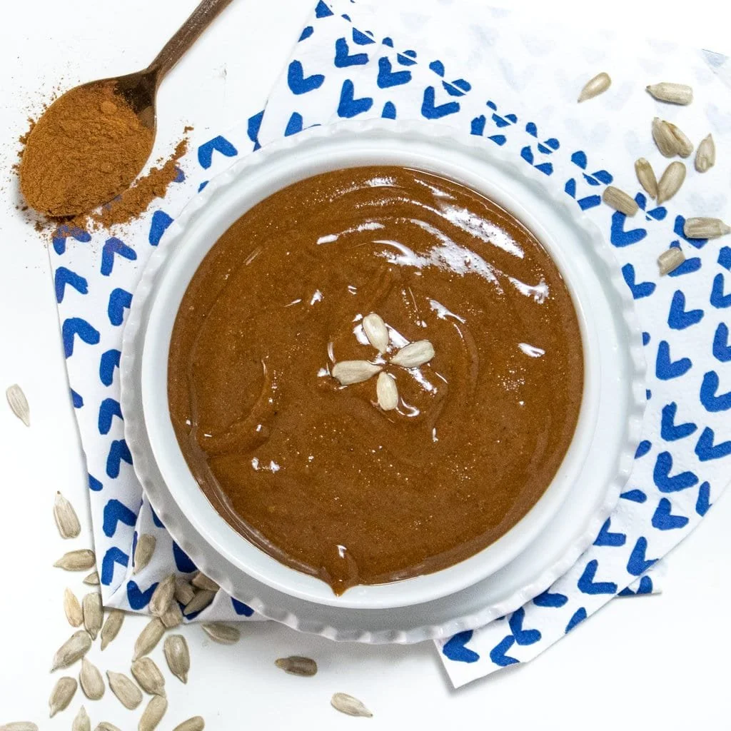 Homemade spiced sunflower seed butter in a jar with toppings, ideal for busy moms.