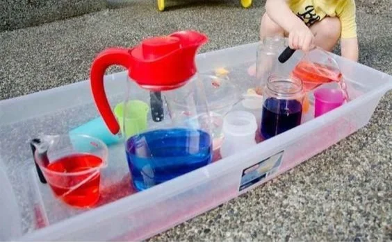 Toddlers engaged in pouring station activities to develop skills and creativity.