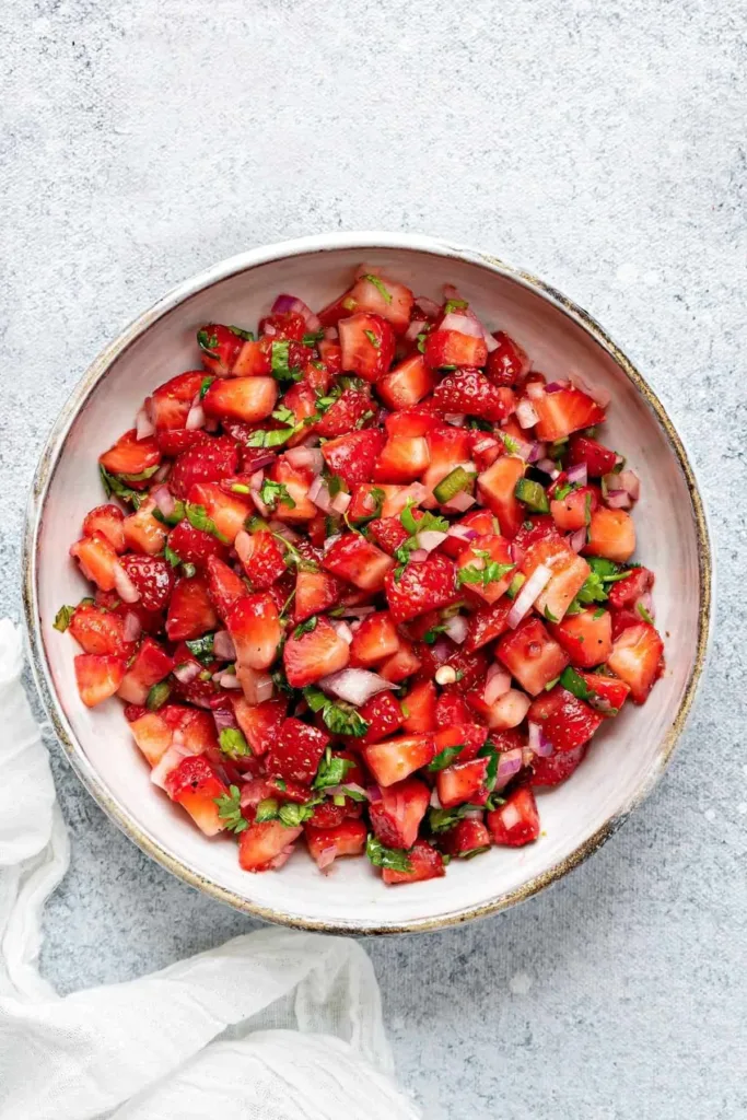 Colorful strawberry salsa served in a bowl with tortilla chips.